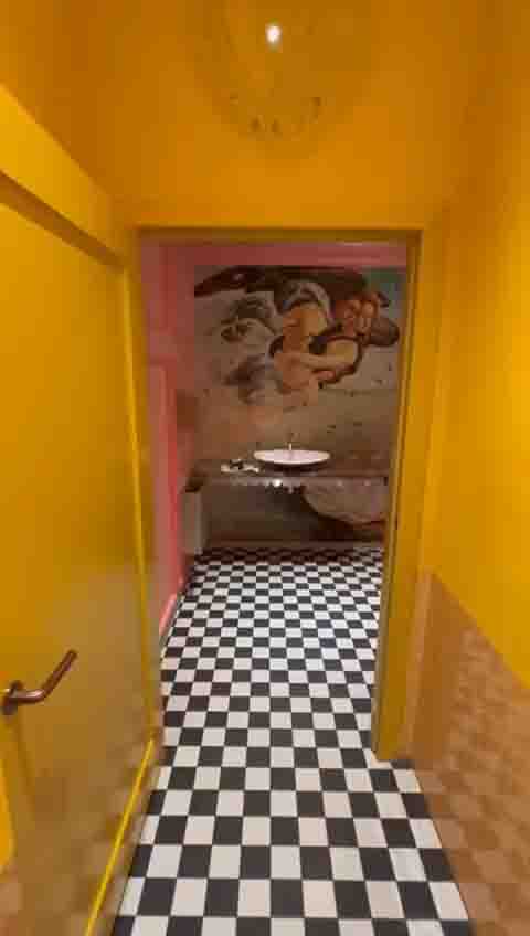 Ragu Lazienka 2 Wnętrze łazienki w RAGU Leszno z żółtym korytarzem, posadzką w szachownicę i grafiką ścienną przedstawiającą anioła