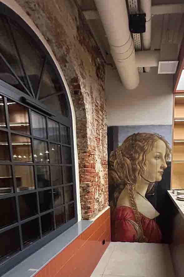 Ragu drzwi wejsciowe do Grafika strukturalna z renesansowym portretem kobiety na ścianie w restauracji RAGU Leszno, obok zabytkowej cegły i łukowego okna