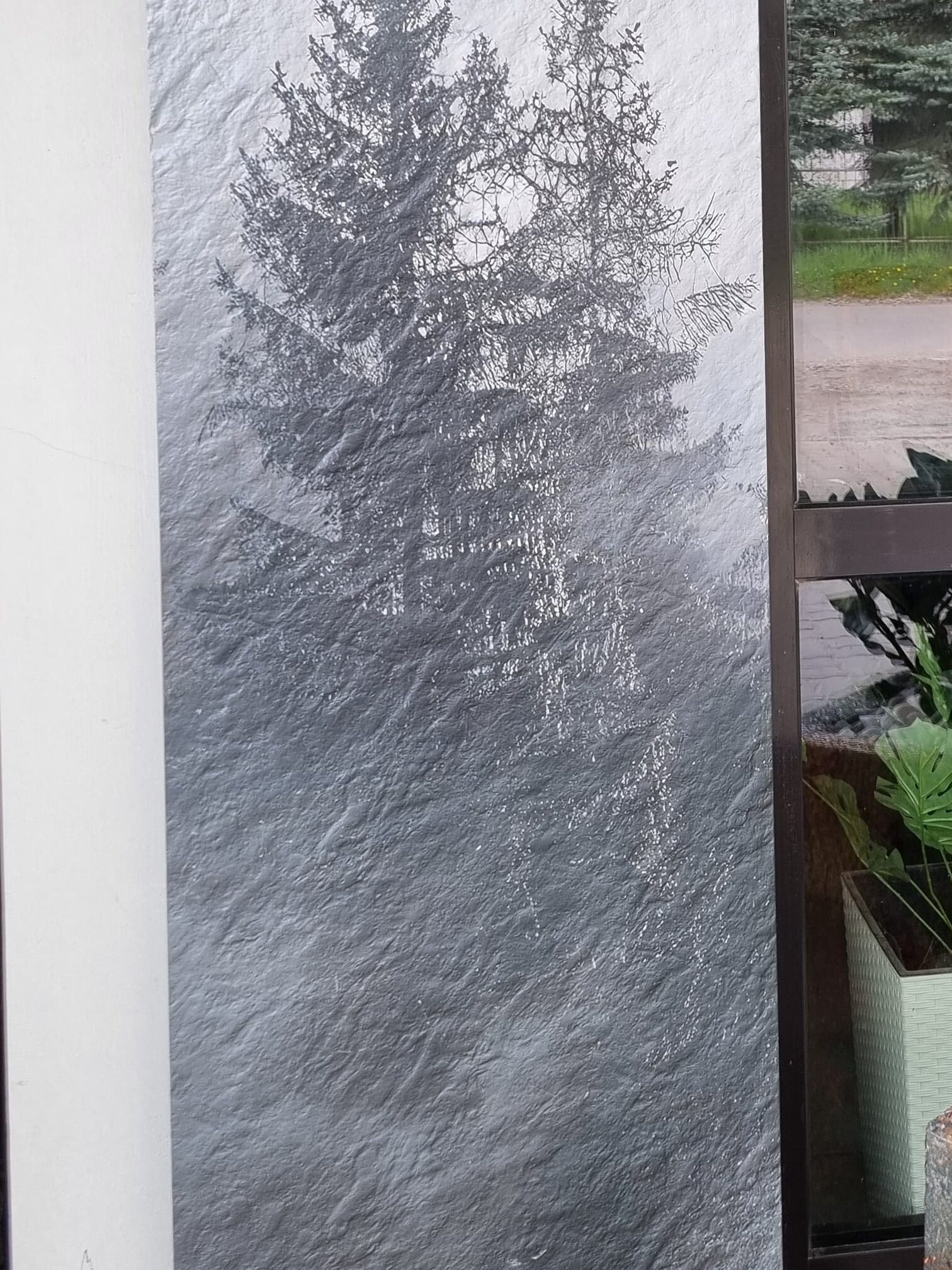 Panel dekoracyjny z grafiką drzew na elewacji przy wejściu do budynku SmartFresk