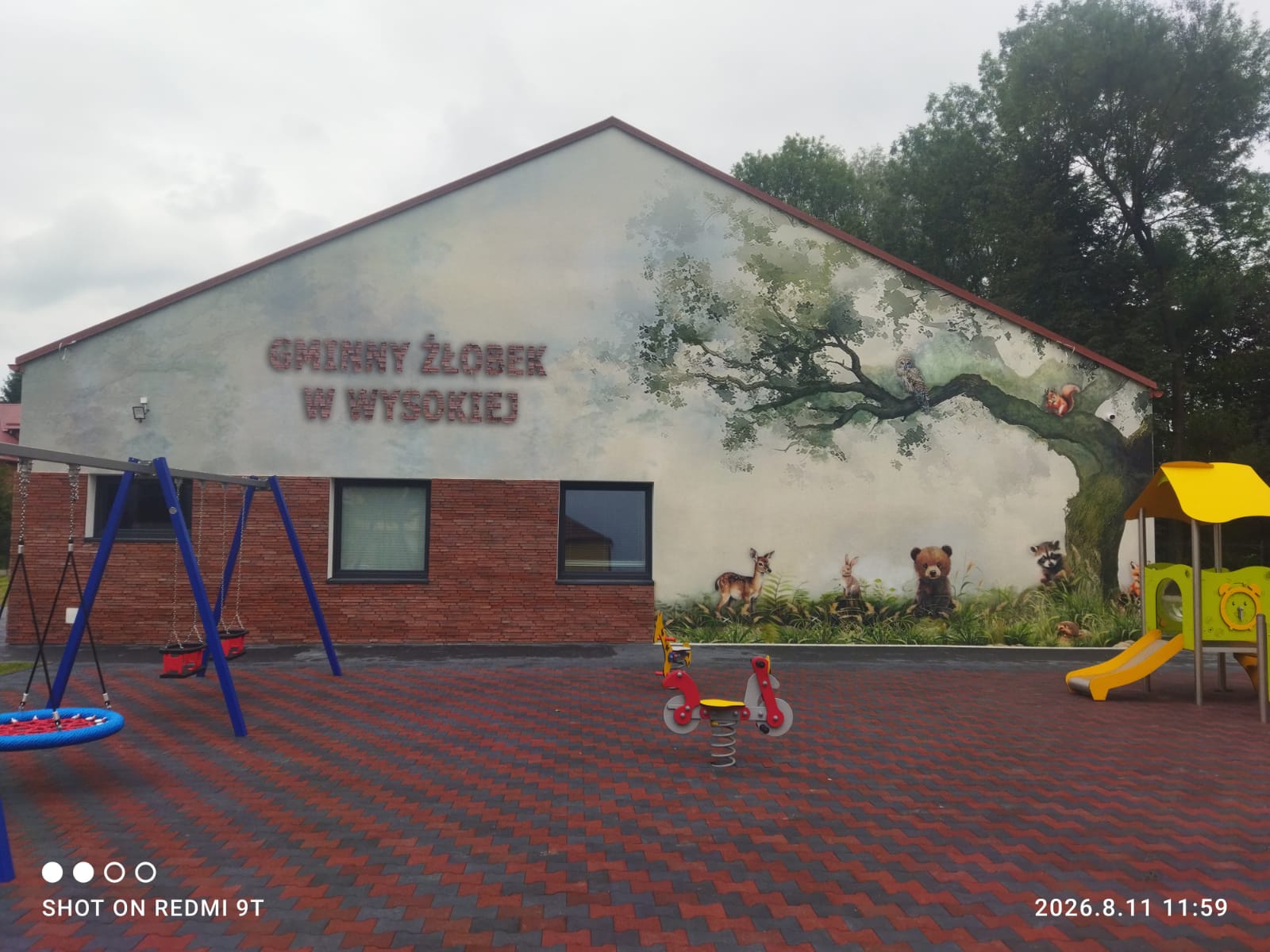 Mural leśny na elewacji Gminnego Żłobka w Wysokiej — dąb z sową i wiewiórką nad placem zabaw, technika DTS SmartFresk